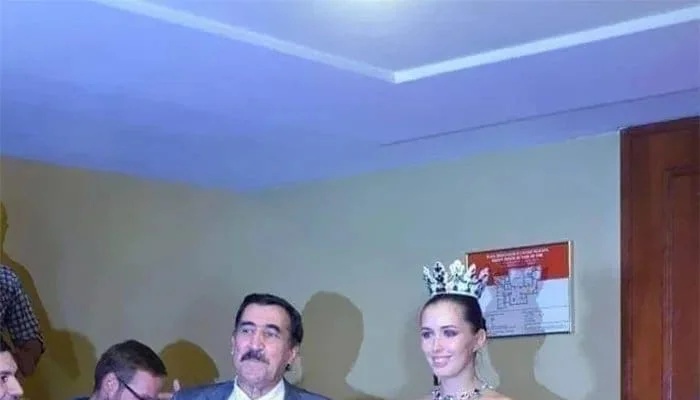 A bride in a wedding dress with Putin wearing angel wings and a black belt.