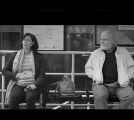Grandfather talking to a pregnant woman at a bus stop.