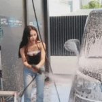 A college girl washing a car.