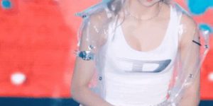 ITZY YUNA is wearing a sleeveless shirt that bows down to put down the water bottle.