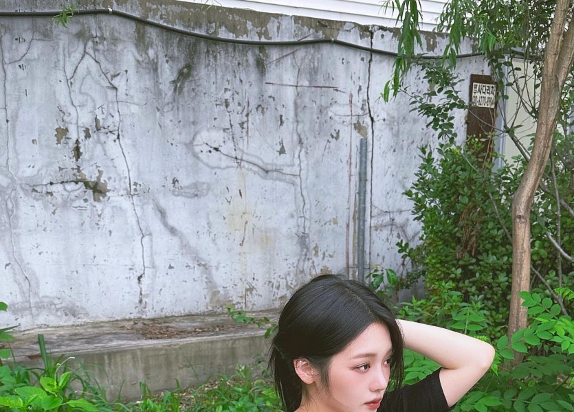 Noh Jiseon sitting at an outdoor table, black ribbed shirt, heavy chest line