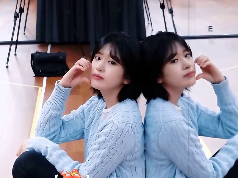 Ahn Yujin's GIF is leaning on the mirror and making a cheek heart